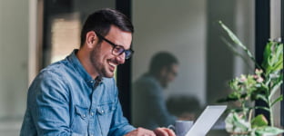 Homem branco, com cabelo curto e óculos, mexendo no notebook.