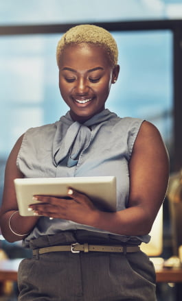 Mulher negra, com cabelo curto, olhando para o tablet.